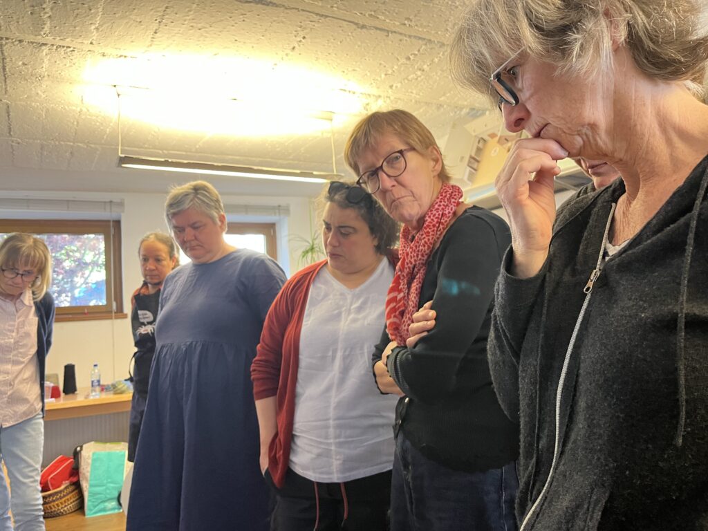 Group of adults standing in a room, looking down at something on a table.