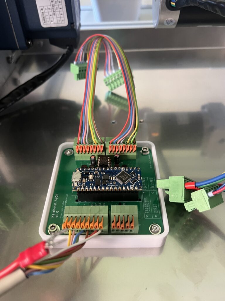 Control electronics inside a metal enclosure: green terminal blocks with multi-colored wires connected to a PCB and an Arduino-like module.
